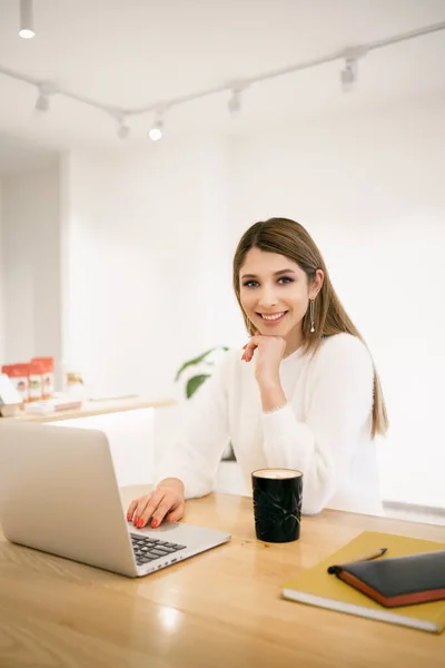 Jovem do sexo feminino no café usando laptop e beber latte — Fotografia de Stock