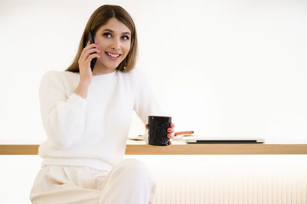 笑着在智能手机上聊天的女人在屋里喝咖啡 — 图库照片