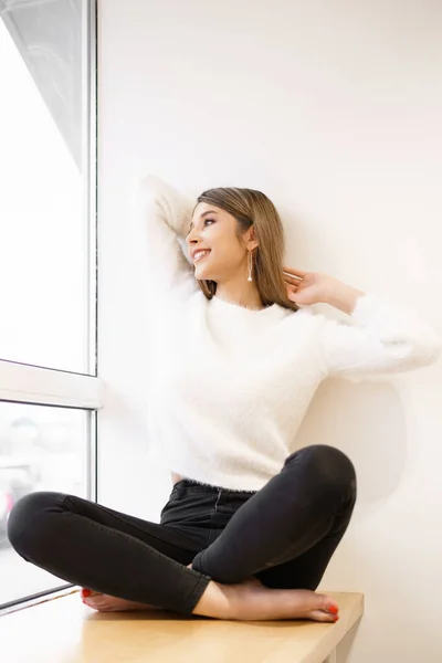 Mujer sonriente sentada cerca de la ventana — Foto de Stock