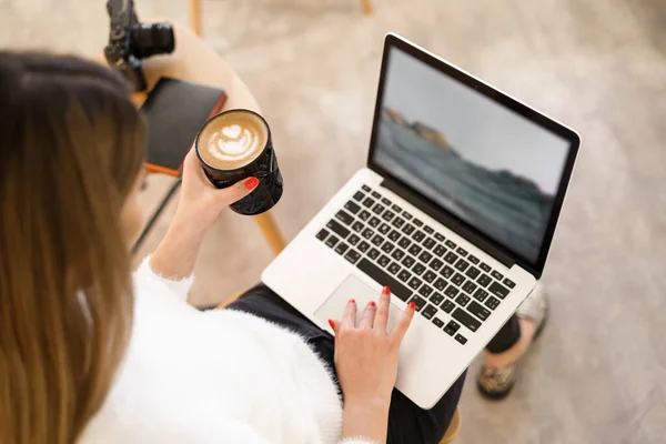 Jong vrouw in cafe met behulp van laptop en het drinken van latte — Stockfoto