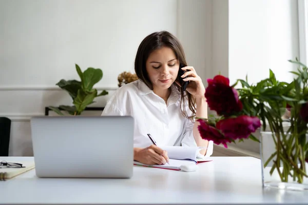 Jovem alegre bela mulher falando no telefone e usando laptop — Fotografia de Stock