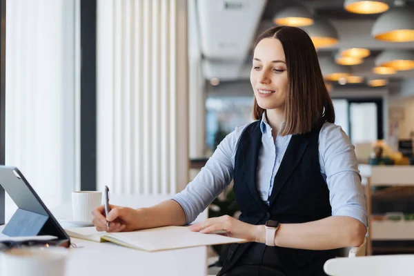 Femme prenant des notes alors qu'elle était assise seule à la table — Photo