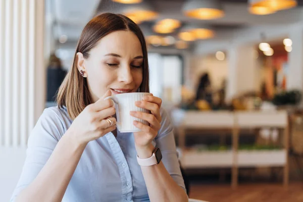 Retrato de una joven bebiendo café en la mesa en la cafetería —  Fotos de Stock