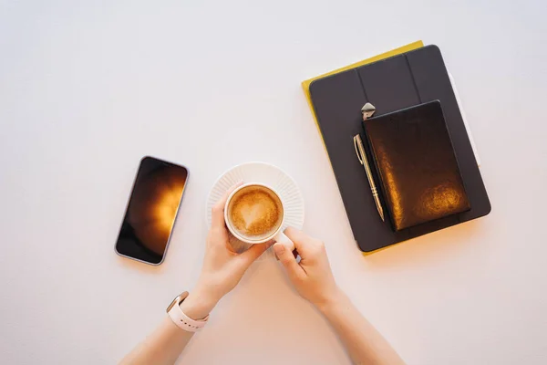 Top view vrouw handen met een kopje koffie, tablet, telefoon — Stockfoto