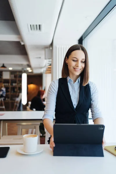 Portrait de jeune femme buvant du café à table avec tablette dans un café — Photo