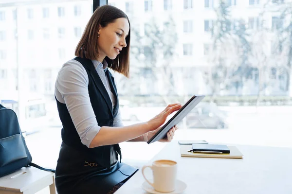 Portrait de jeune femme buvant du café à table avec tablette dans un café — Photo