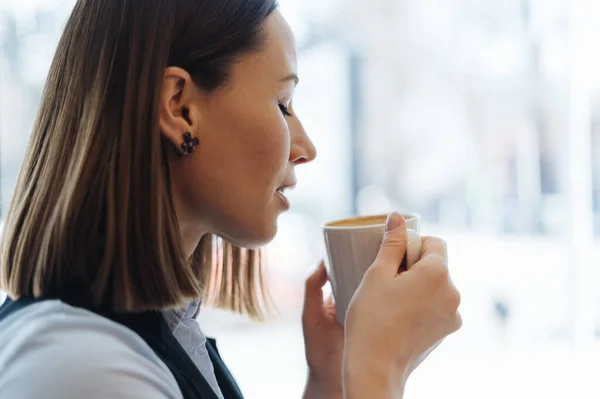 Portret van een jonge vrouw die koffie drinkt aan tafel in café — Stockfoto