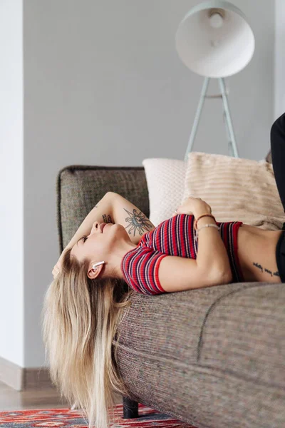 Молодая женщина слушает музыку лежа диван дома — стоковое фото