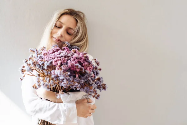 Giovane donna in camicia bianca in posa con un mazzo di fiori — Foto Stock