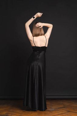 Uzun siyah elbiseli zarif bir kadının yüksek moda portresi.