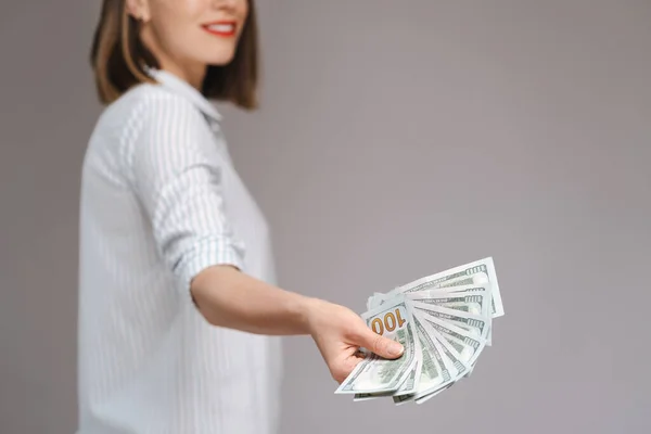 Woman holding money on gray background — Stock Photo, Image