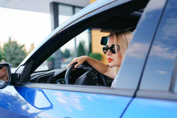 Femme en lunettes de soleil conduisant une voiture — Photo