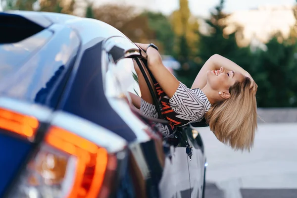Веселая женщина вылезает из окна своей машины — стоковое фото
