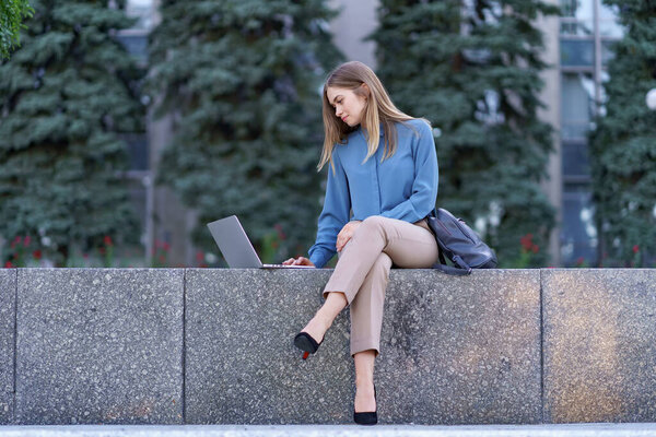 Young women working on laptop in the city square