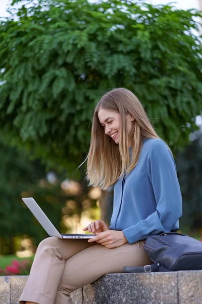 Молодые женщины, работающие на ноутбуке на городской площади — стоковое фото