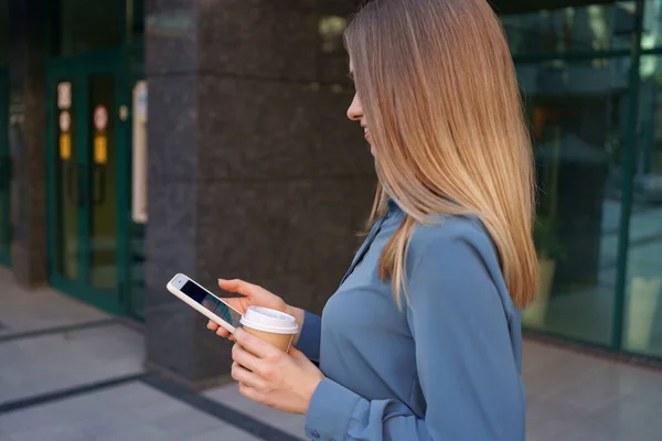 Женщина использует современный смартфон и пить кофе, чтобы пойти — стоковое фото