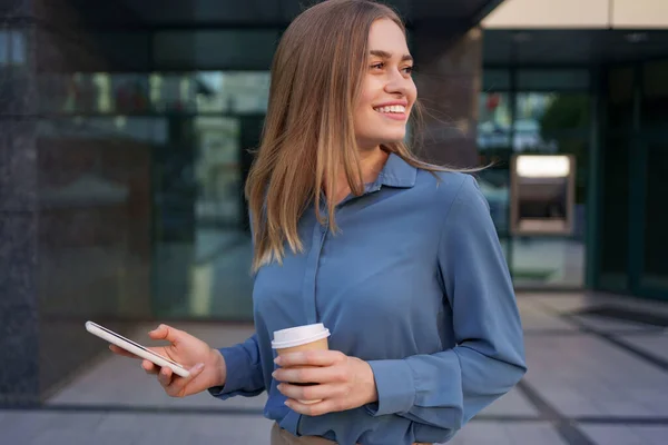 Mulher usando smartphone moderno e beber café para ir — Fotografia de Stock