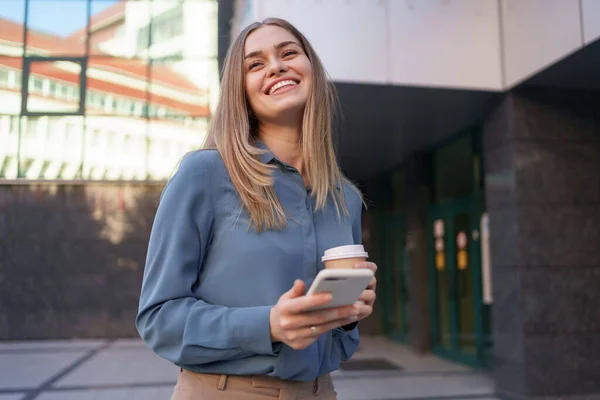 Mulher usando smartphone moderno e beber café para ir — Fotografia de Stock