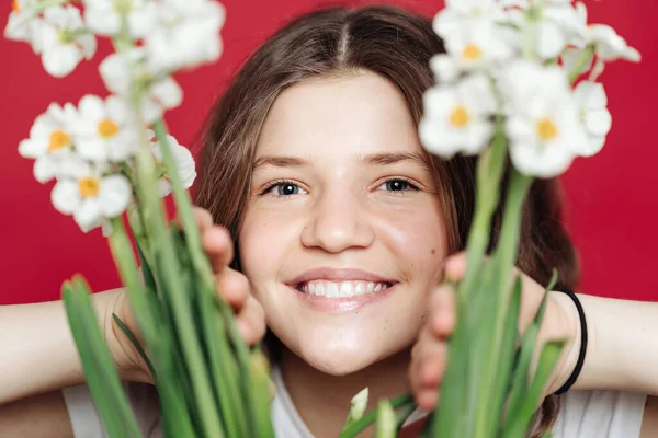 Flicka poserar med vita blommor på röd bakgrund — Stockfoto