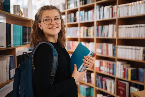 Adolescente chica escogiendo un libro en la biblioteca — Foto de Stock