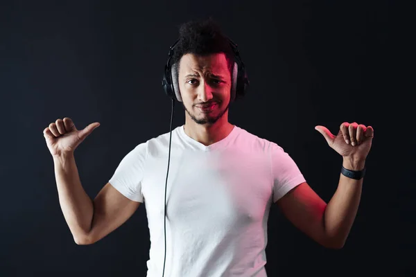 Carefree dark skinned guy portrait wearing headphones on black background — Stock Photo, Image