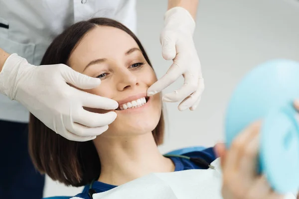 치과 의사들의 손 과 치료 후 거울을 보는 행복 한 환자 — 스톡 사진