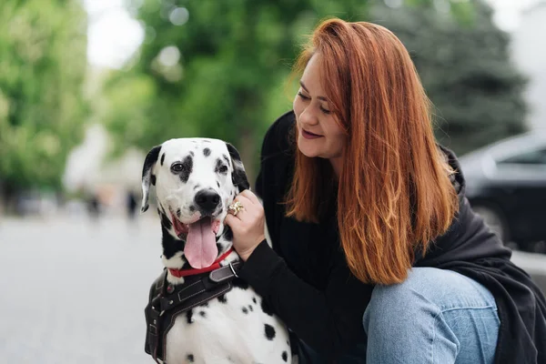 Όμορφη γυναίκα ποζάρουν και αγκαλιάζει dalmatian σκυλί στο δρόμο φόντο της πόλης — Φωτογραφία Αρχείου