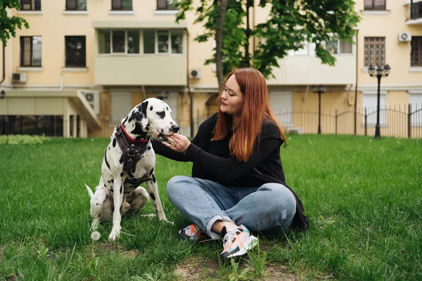 Ładna kobieta pozowanie i przytulanie dalmatyński pies na ulicy tło miasta — Zdjęcie stockowe