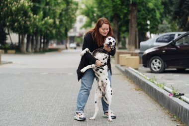 Kadın şehirde dalmaçyalı hayvanını tartışıyor ve eğitiyor.