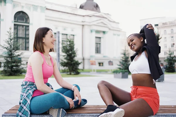 Zwei multiethnische kurvige Mädchen entspannen sich nach einer Trainingseinheit, kommunizieren im Freien. — Stockfoto