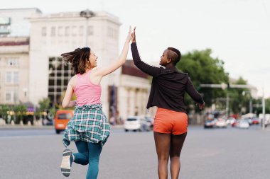 Şehir sokaklarında koşuşturan iki etnik kız, açık havada iletişim kuruyor..