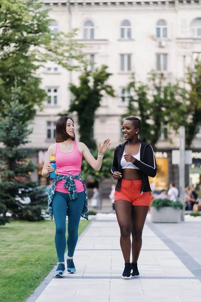 Dvě multietnické dívky procházky na cvičení, venkovní komunikace. — Stock fotografie
