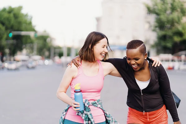 Dos chicas multiétnicas caminando para una sesión de ejercicio, comunicándose al aire libre. — Foto de Stock