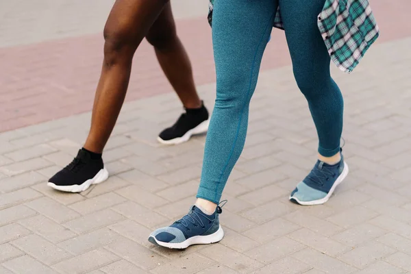 Zwei multiethnische Mädchen joggen durch die Straßen der Stadt und kommunizieren im Freien. — Stockfoto