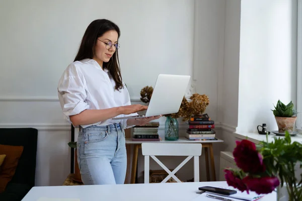 Бізнес-леді працює на портативному комп'ютері, сидячи вдома і керуючи своїм бізнесом через домашній офіс — стокове фото