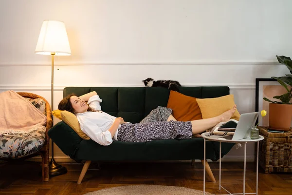 Молода жінка розслабляється лежачи на дивані вдома — стокове фото