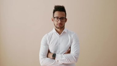 Kollarını kavuşturmuş genç adam gülümseyeceğine kameraya bakıyor.