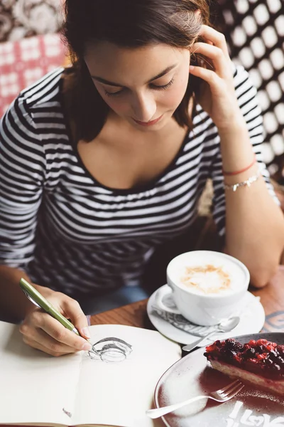Meisje tekening van een kopje koffie in het notitieblok — Stockfoto