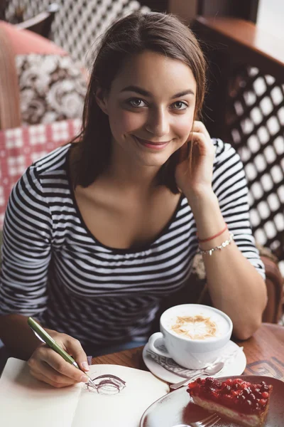 Flicka ritar en kopp kaffe i anteckningsboken — Stockfoto