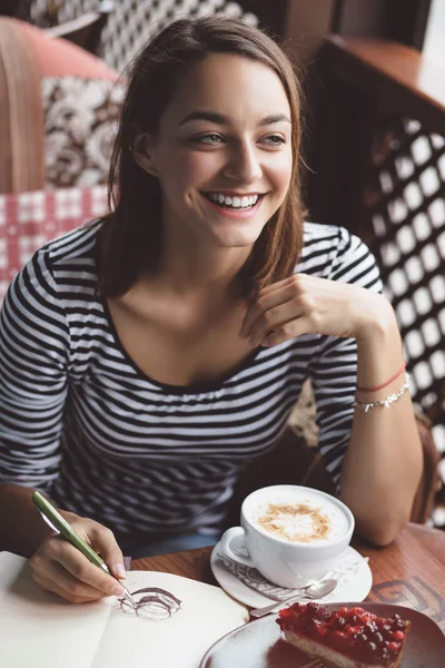 Meisje tekening van een kopje koffie in het notitieblok — Stockfoto