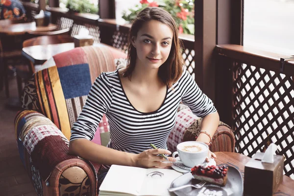 Meisje tekening van een kopje koffie in het notitieblok — Stockfoto