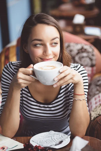 Молодая женщина пьет кофе в городском кафе — стоковое фото