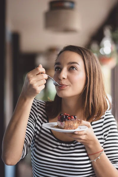 Молода жінка їсть полуничний чізкейк — стокове фото
