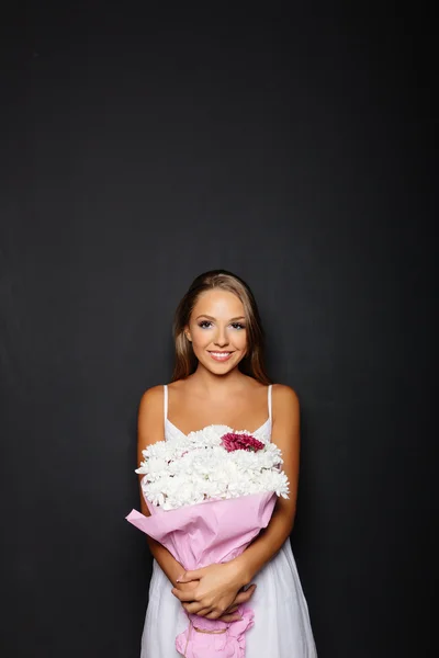 Молодая женщина с букетом цветов на черном фоне — стоковое фото