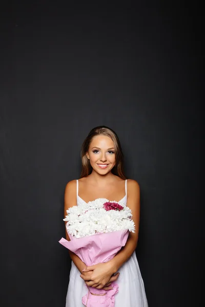 Giovane donna con mazzo di fiori su sfondo nero — Foto Stock