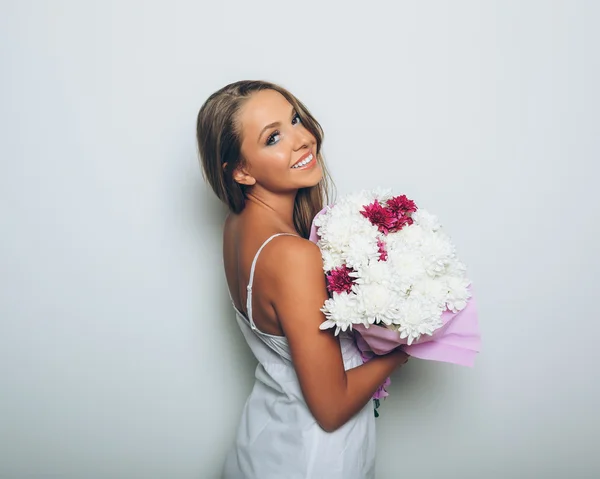 Junge Frau mit Blumenstrauß auf weißem Hintergrund — Stockfoto