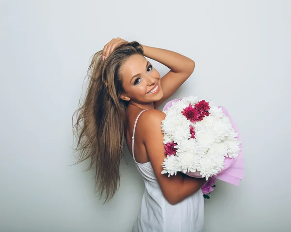 Ung kvinna med bukett blommor på vit bakgrund — Stockfoto