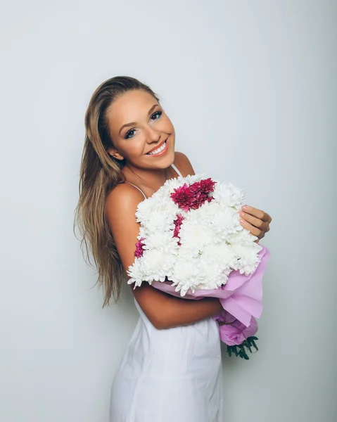 Молодая женщина с букетом цветов на белом фоне — стоковое фото