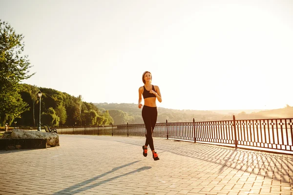 Systemem kobieta. Biegacz jogging w jasnym świetle słonecznym. Oferuje zakw żeński — Zdjęcie stockowe