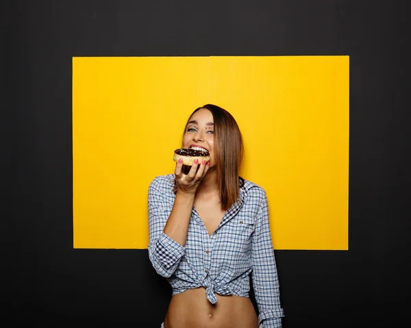 Menina comendo donut com cobertura de chocolate — Fotografia de Stock
